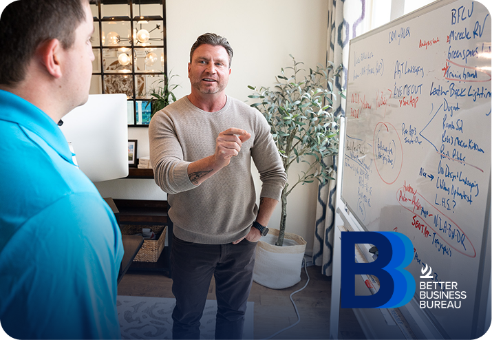 Two colleagues talking beside a whiteboard at a BBB office