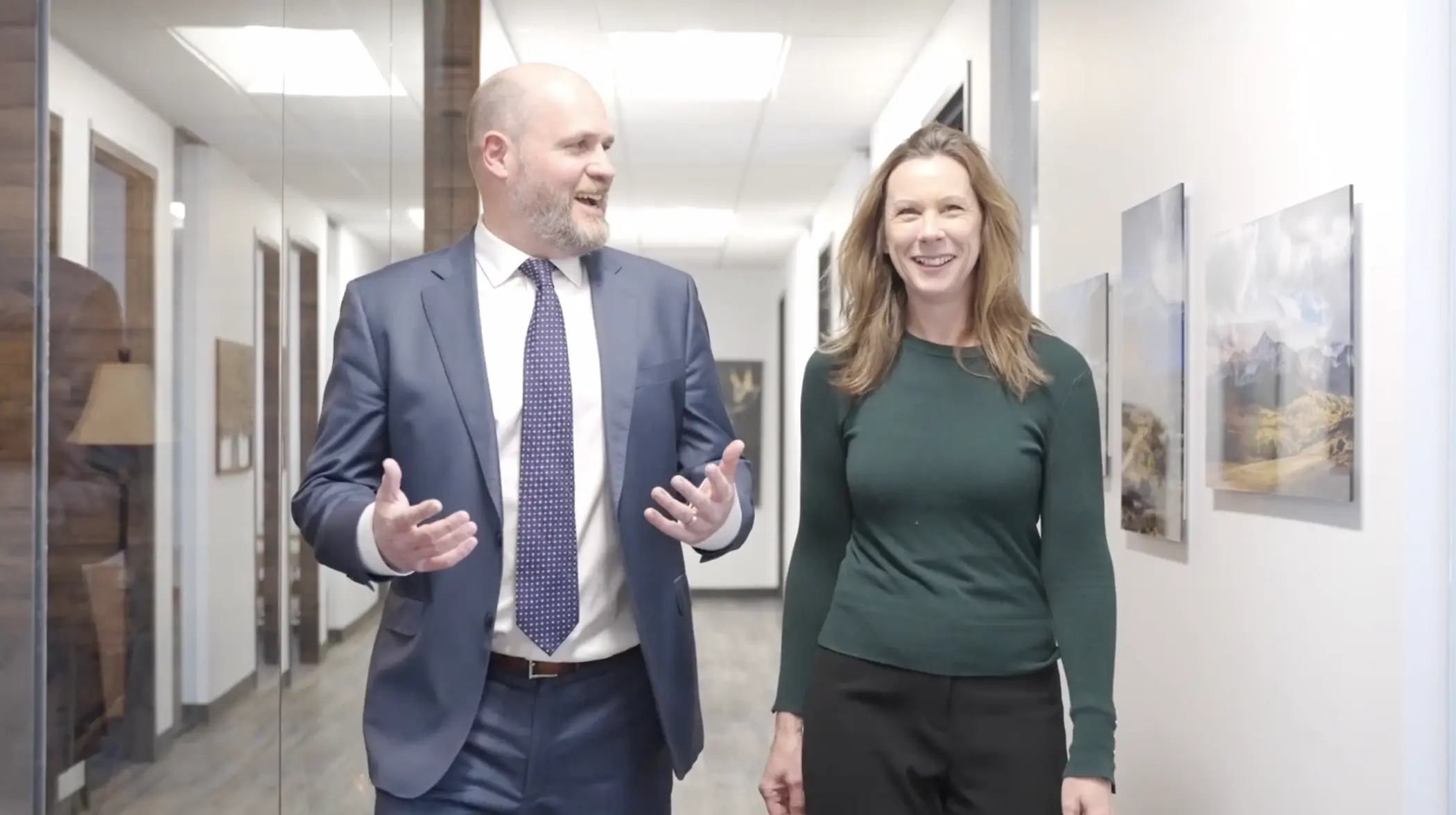 Two business owners walking down an office hallway